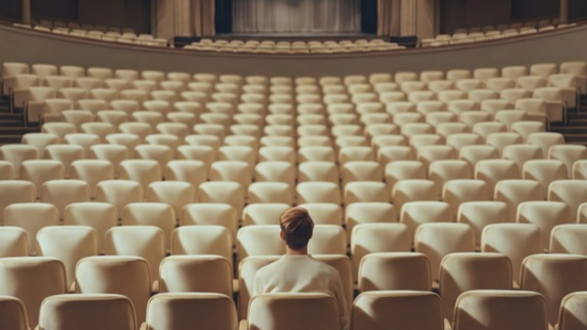 One person sits alone in a huge empty auditorium