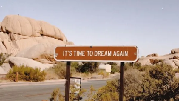 Pouštní cedule s nápisem It's time to dream again mezi skalami