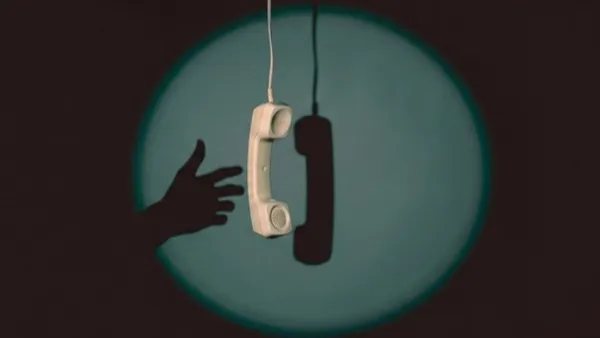 Ruka sahá po zavěšeném telefonním sluchátku ve světelném kruhu