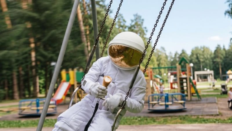 Ilustrace astronauta na houpačce ve vesmíru s planetami a hvězdami