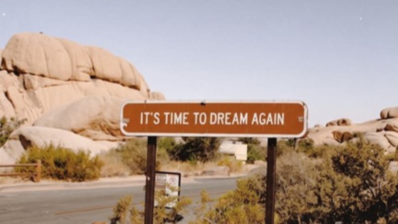 Pouštní cedule s nápisem It's time to dream again mezi skalami
